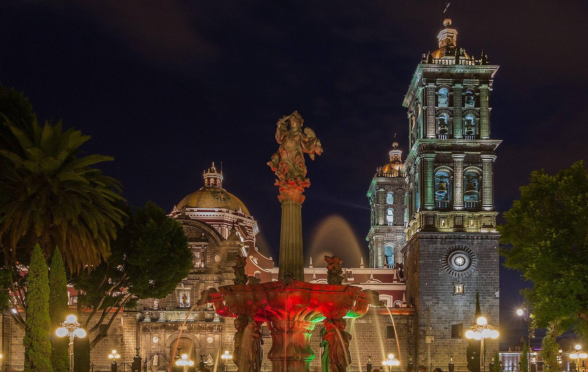 Catedral de Puebla iluminada de noche junto a la fuente del Zócalo
